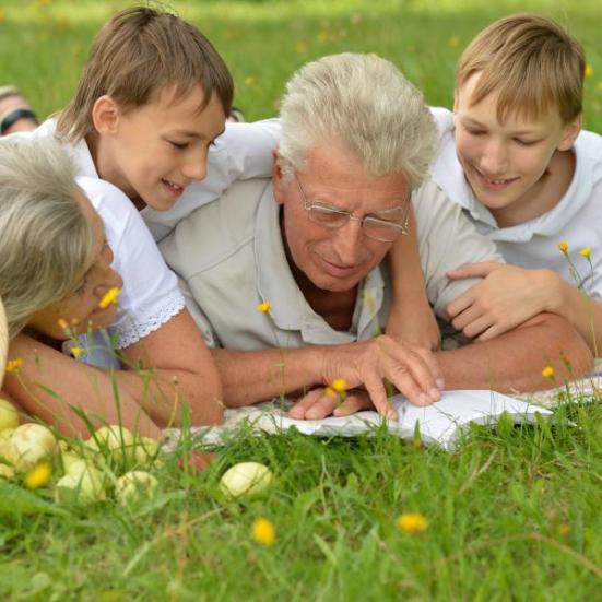 En bedstefar læser højt for bedstemor og børnebørn